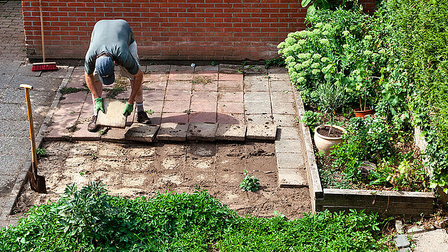 man haalt tegels uit de tuin